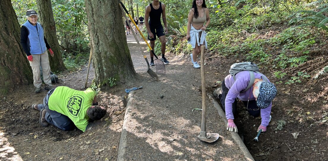 Hikers almost pause while Matt, Mari, and Janet work on clearing a culvert.