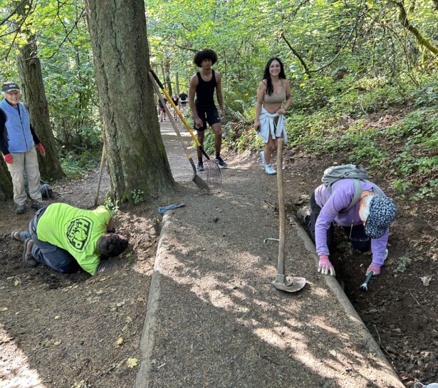 Hikers almost pause while Matt, Mari, and Janet work on clearing a culvert.