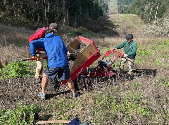 Marlon, Joe, and Sony spreading gravel from a power-wheelbarrow.