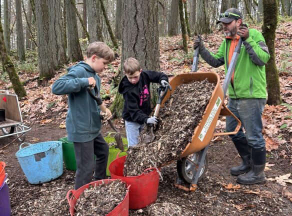 Joe helping Oliver and Fletcher fill the bags with mulch.