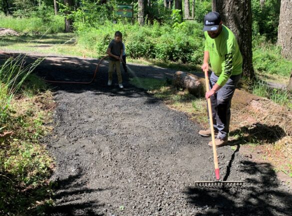 Matt doing a final raking and Naith watering the gravel before compacting begins.